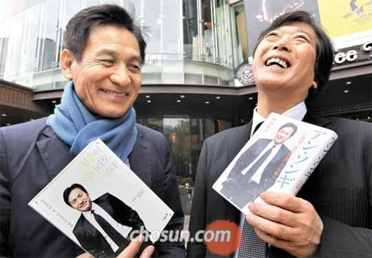▲ソウル市中区の明宝アートホールで17日、俳優アン・ソンギは自身の評伝を書いた村山俊夫氏と対面した。写真は日本語版と韓国語版の本を手にする2人。／写真＝李徳熏（イ・ドクフン）記者