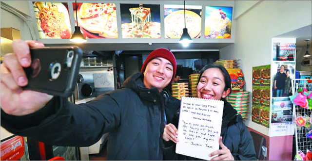 2月11日、ソウル市銅雀区のピザ店で、外国人観光客が芳名録を手に自撮り写真を撮っている。 