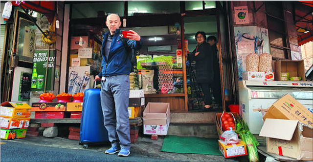 劇中、「ウリスーパー」として登場したアヒョン洞のスーパー前で記念撮影をする日本人観光客。